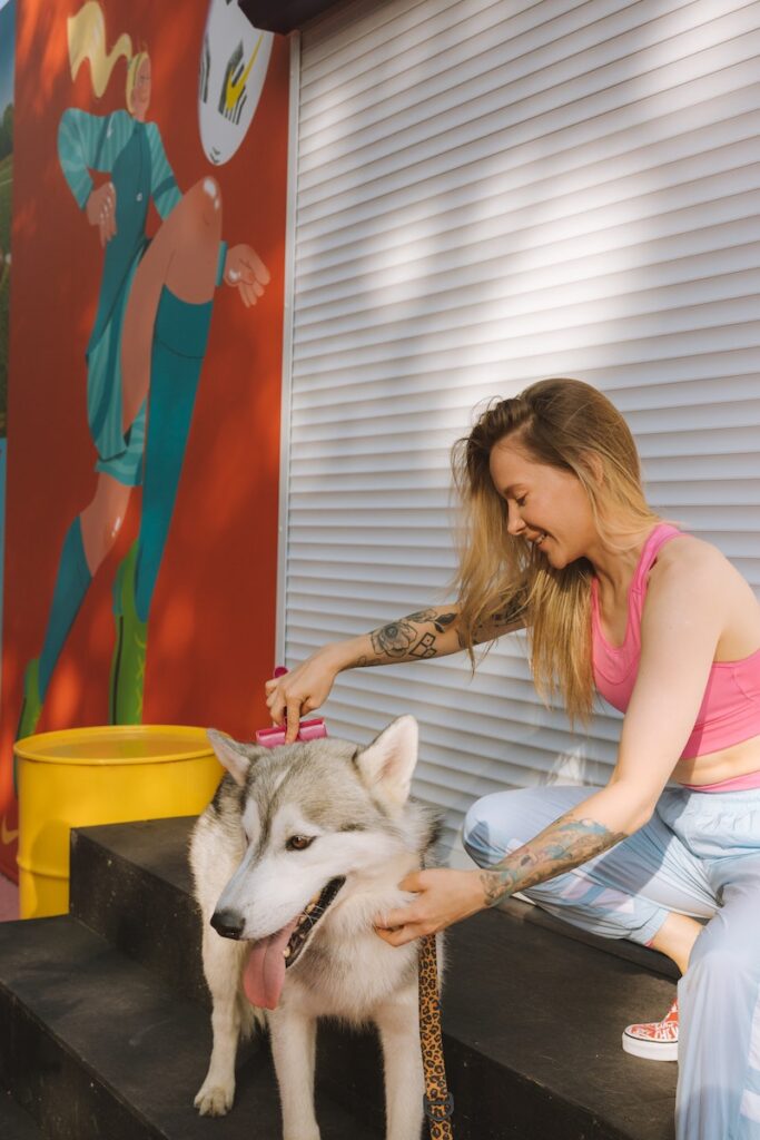 A Woman in Pink Tank Top Combing a Dog